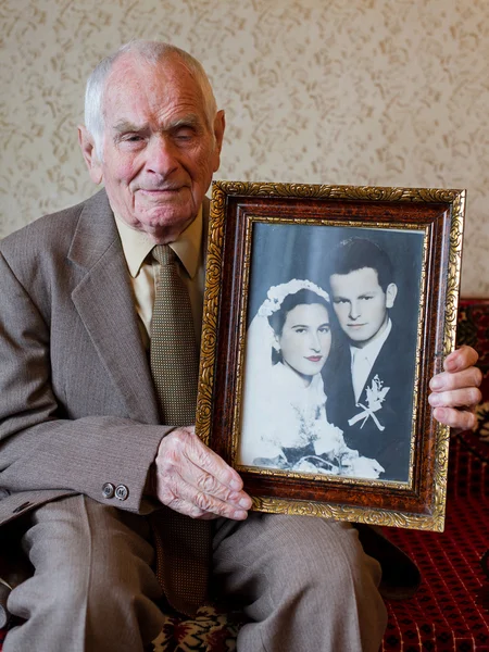 Handsome 80 plus year old senior man holding his wedding photograph. Love forever concept. — Stock Photo, Image