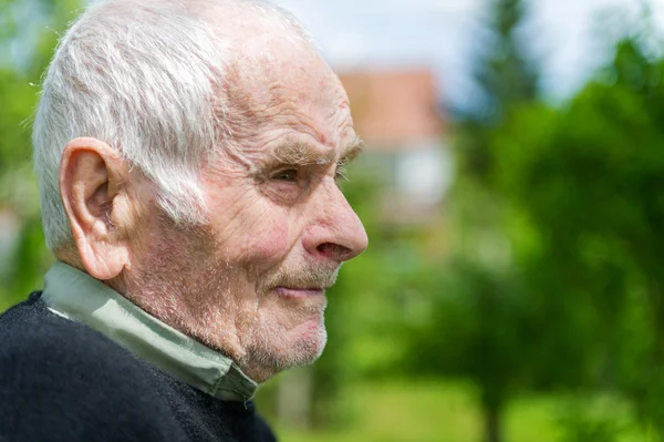 Stilig 80 plus år gammal senior man poserar för ett porträtt i hans trädgård. — Stockfoto