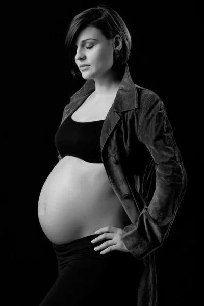 Attraente giovane donna incinta con la pancia nuda su sfondo nero — Foto Stock
