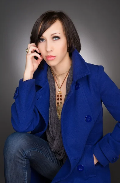Imagen en color vertical de una hermosa mujer joven profunda en pensamientos. Usando abrigo de invierno azul oscuro. Retrato de estudio — Foto de Stock