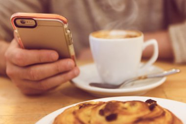 Her zaman temas halinde. Ayrıntılı görüntü kahve içme ve restoranda kahvaltı yaparken akıllı telefon tutarak tanınmayan adam.