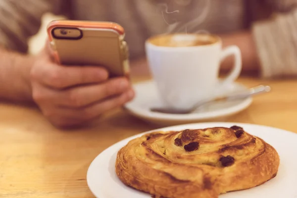 Sempre em contacto. Imagem de detalhe do homem irreconhecível bebendo café e segurando telefone inteligente enquanto toma café da manhã no restaurante . — Fotografia de Stock