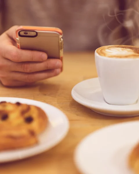 Sempre em contacto. Imagem de detalhe do homem irreconhecível bebendo café e segurando telefone inteligente enquanto toma café da manhã no restaurante . — Fotografia de Stock