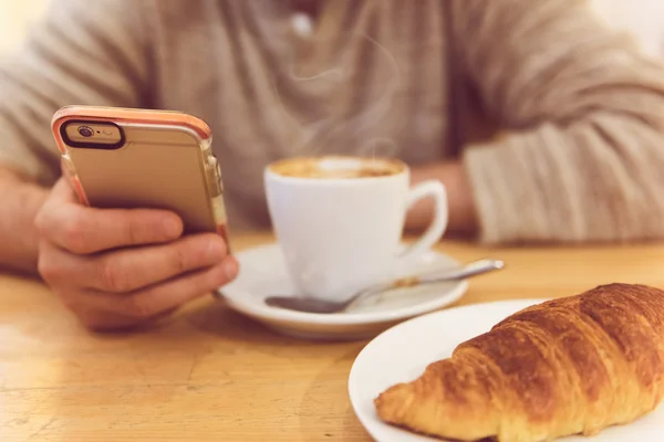 Sempre em contacto. Imagem de detalhe do homem irreconhecível bebendo café e segurando telefone inteligente enquanto toma café da manhã no restaurante . — Fotografia de Stock