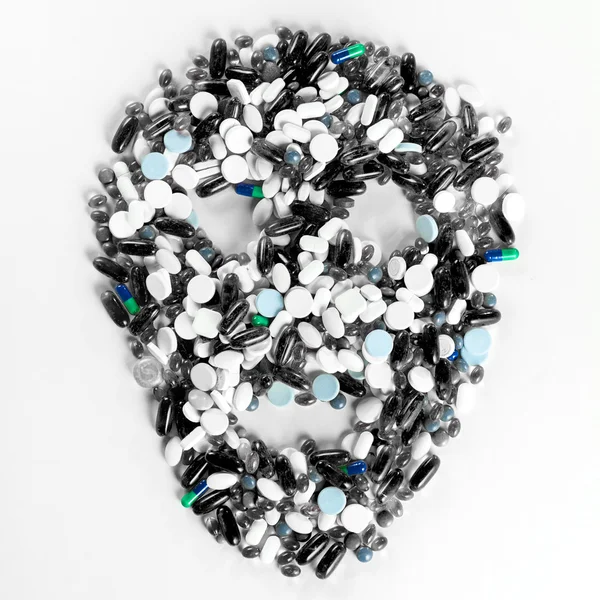 Comprimidos, comprimidos e cápsulas, que formam um crânio assustador no fundo branco — Fotografia de Stock