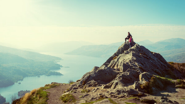 Two female hikers on top of the mountain enjoying valley view, Ben A'an, Loch Katrine, Highlands, Scotland, UK