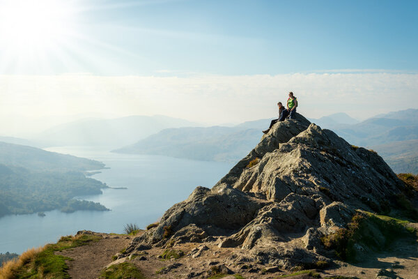 Two female hikers on top of the mountain enjoying valley view, Ben A'an, Loch Katrine, Highlands, Scotland, UK