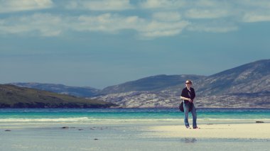 Young Caucassian woman enjoying holiday on a white sandy beach with turquoise water, Luskentyre, Isle of Harris, Scotland clipart
