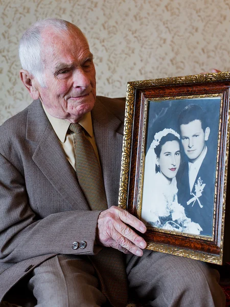 Stilig 80 plus år gammal senior mannen hålla sitt bröllop fotografi. Love forever koncept. — Stockfoto