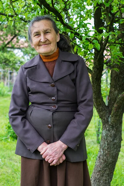 Vackra 80 plus år gammal senior kvinna poserar för ett porträtt i hennes trädgård. — Stockfoto