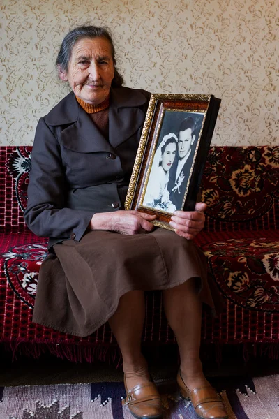 Beautiful 80 plus year old senior woman holding her wedding photograph. Love forever concept. — Stock Photo, Image