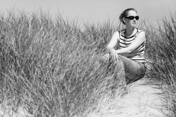 Jovem mulher sentada em dunas de areia entre grama alta relaxante, desfrutando da vista no dia ensolarado, Luskentyre, Ilha de Harris, Escócia — Fotografia de Stock