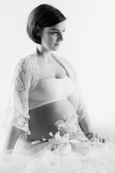 Pregnant woman belly with white flower in light tones,  on white background — Stock Photo, Image