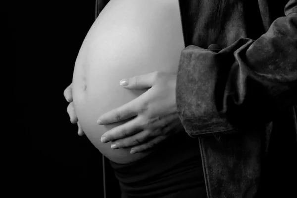 Afbeelding van zwangere vrouw aanraken haar buik met handen op zwarte achtergrond — Stockfoto