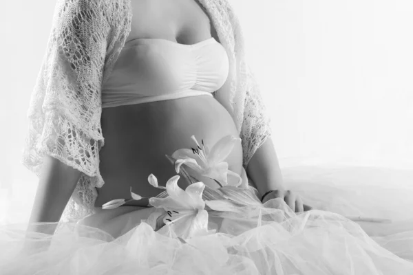 Mulher grávida barriga com flor branca em tons claros, no fundo branco — Fotografia de Stock