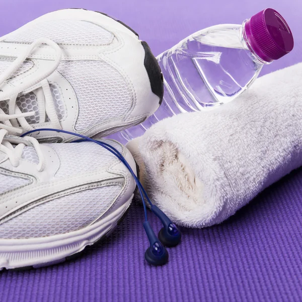 Fundo de fitness, tênis, fones de ouvido, garrafa de água e toalha — Fotografia de Stock