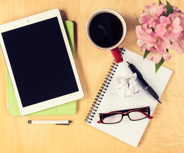 Office tabel met digitale tablet, glazen kopje koffie en notepad lezen. Bekijken van boven met kopie ruimte — Stockfoto