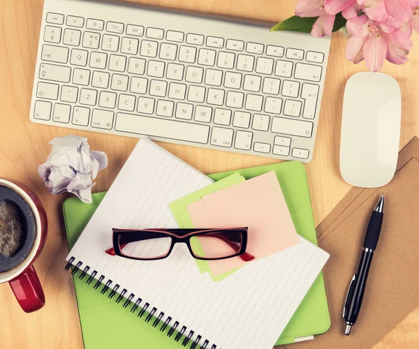 Chaotischer Bürotisch mit Notizblock, Computer, Lesebrille und Kaffeetasse. Blick von oben mit Kopierraum — Stockfoto