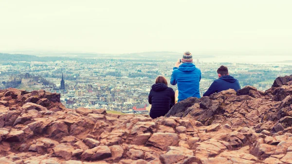Amigos tirando fotos de Edimburgo do topo do assento Arthurs, vulcão antigo, Escócia, Reino Unido, usando smartphone — Fotografia de Stock