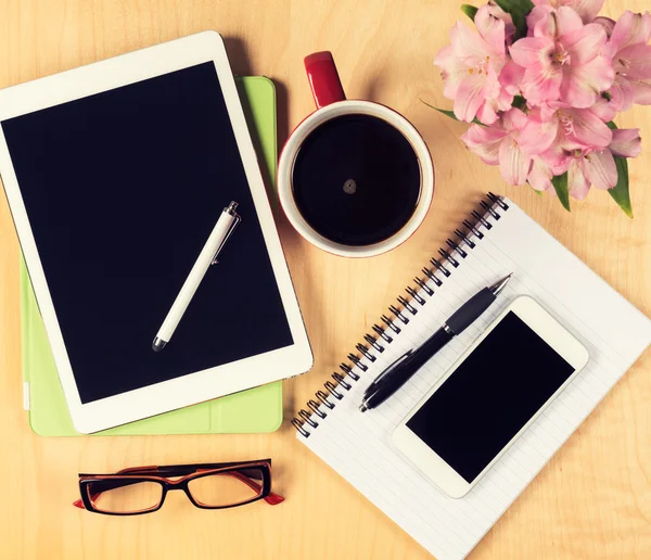 Messy office table with digital tablet, smartphone, reading glasses, notepad and cup of coffee. View from above with copy space — Stock Photo, Image