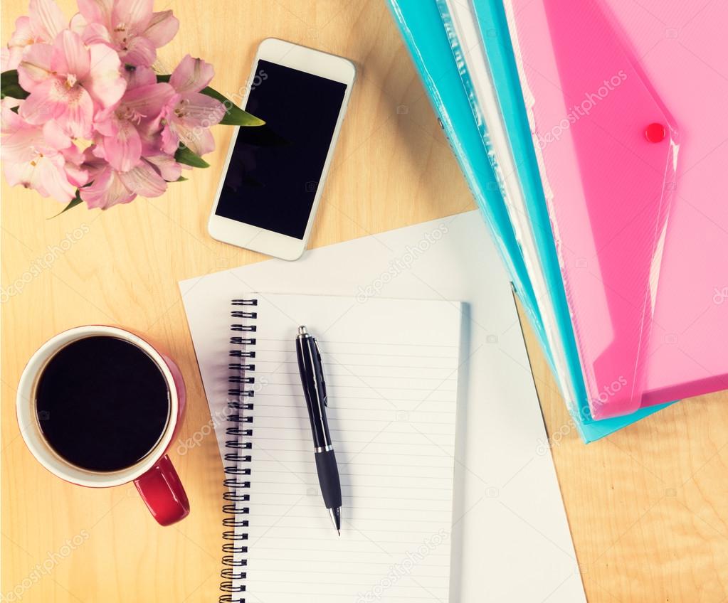 Office table with smartphone, empty sheet of paper, filling folders and cup of coffee. View from above with copy space