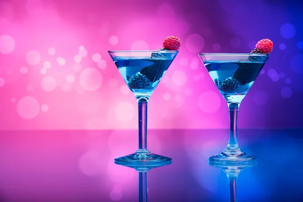 Colourful cocktails garnished with berries, background with light effects — Stock Photo, Image