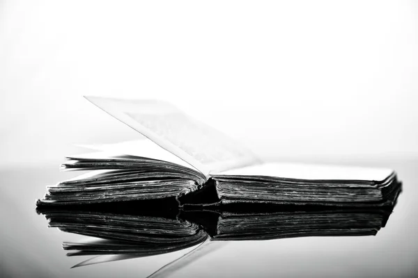 Immagine in bianco e nero ad alto contrasto di un vecchio libro sulla superficie riflettente nera — Foto Stock