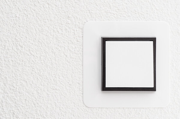 Light switch on white wall, detail shot with copy space