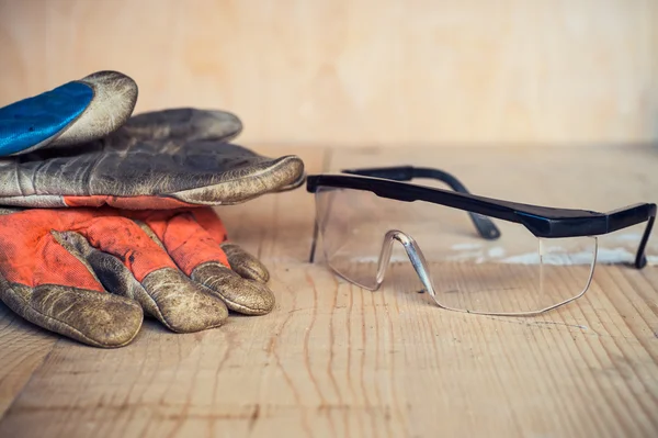 Oude gebruikt veiligheidsbril en handschoenen op houten achtergrond — Stockfoto