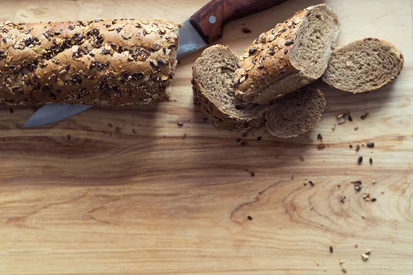 Bagietka chleb żytni posypany różnych nasion na drewnianej desce — Zdjęcie stockowe