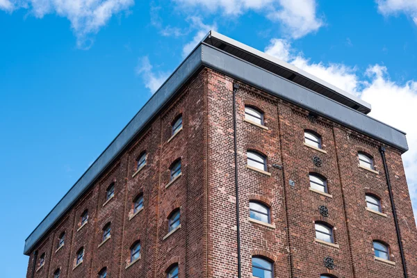 Old red brick building or factory with many small windows with vibrant blue sky — Stock Photo, Image