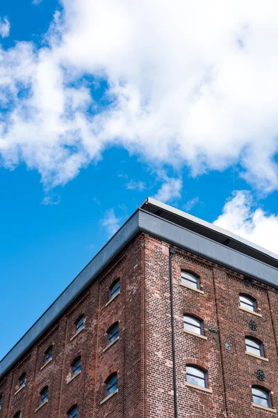 Old red brick building or factory with many small windows with vibrant blue sky — Stock Photo, Image