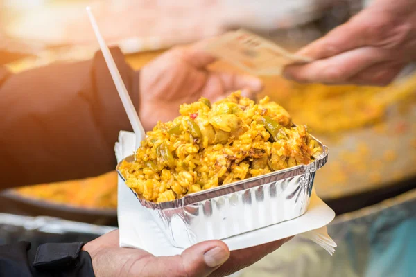 Man buying traditional spanish chicken paella, food market — Stock Photo, Image