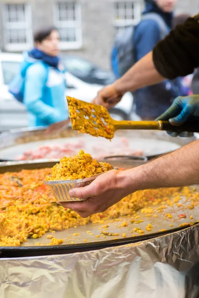 Man serving traditional spanish chicken paella, food market — Stock Photo, Image