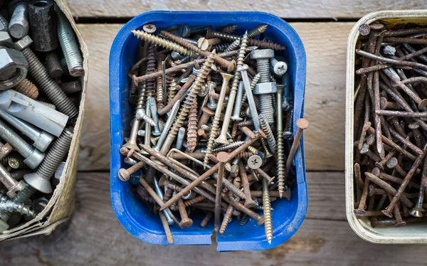 Caixas de parafusos de metal enferrujado velho no fundo de madeira — Fotografia de Stock