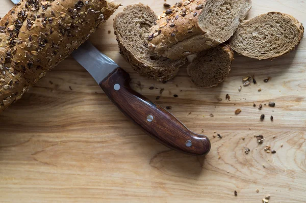 Bagietka chleb żytni posypany różnych nasion na drewnianej desce — Zdjęcie stockowe