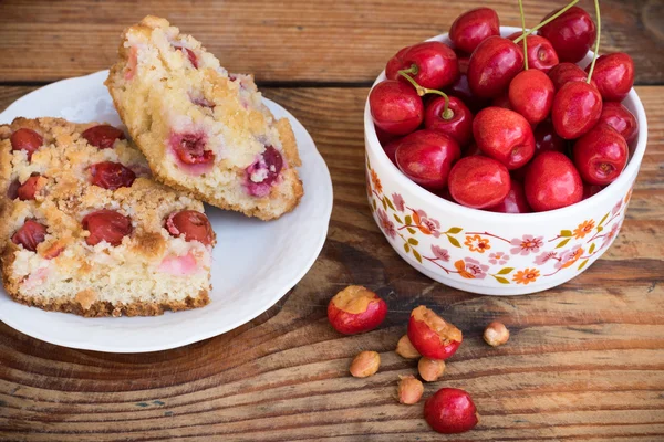 Ripe organic homegrown cherries and cherry cake, on wooden background — Stock Photo, Image
