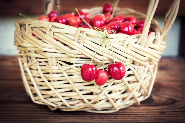 Reife Bio-Kirschen aus eigenem Anbau in einem Korb, auf Holzgrund — Stockfoto