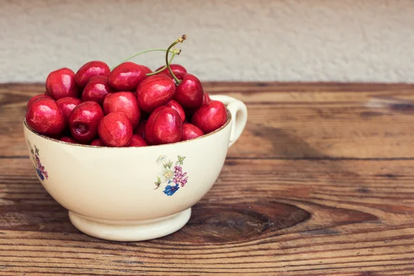 Ripe organic homegrown cherries in a vintage ceramic bowl, on wooden background — Stock Photo, Image