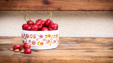 olgun organik homegrown kiraz ve taşlar ahşap arka plan üzerinde bir vintage seramik kase