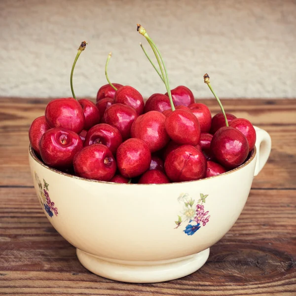 Ripe organic homegrown cherries in a vintage ceramic bowl, on wooden background — Stock Photo, Image