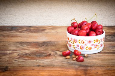 olgun organik homegrown kiraz ve taşlar ahşap arka plan üzerinde bir vintage seramik kase