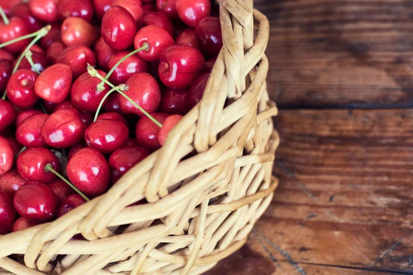 Reife Bio-Kirschen aus eigenem Anbau in einem Korb, auf Holzgrund — Stockfoto