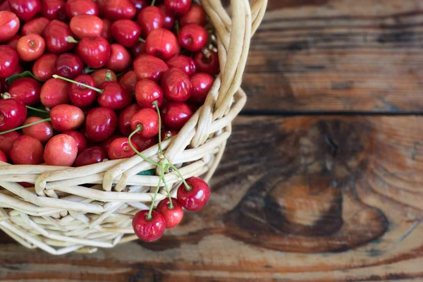 Ripe organic homegrown cherries in a basket, on wooden background — Stock Photo, Image