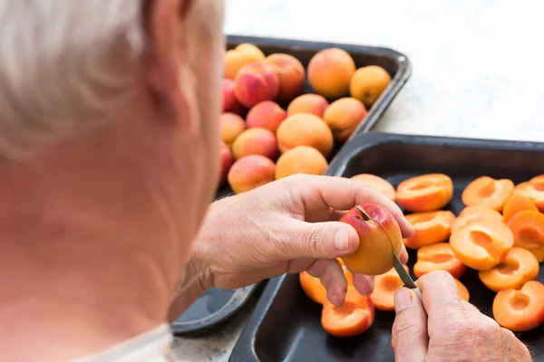 Anonymous man halving fresh homegrown apricots — Stock Photo, Image