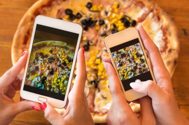 Pizza fotoğraf çekmek için akıllı telefonlar kullanan arkadaşlar