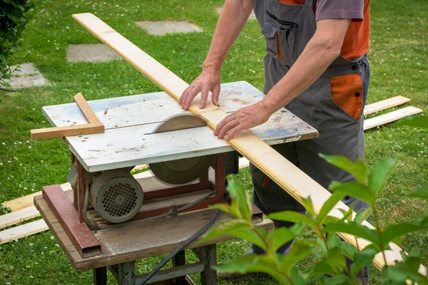 Carpinteiro trabalhando com buzz elétrico viu cortar tábuas de madeira — Fotografia de Stock