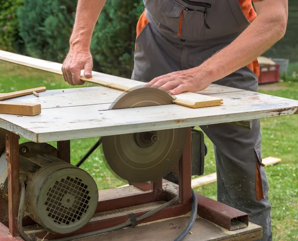 Carpinteiro trabalhando com buzz elétrico viu cortar tábuas de madeira — Fotografia de Stock