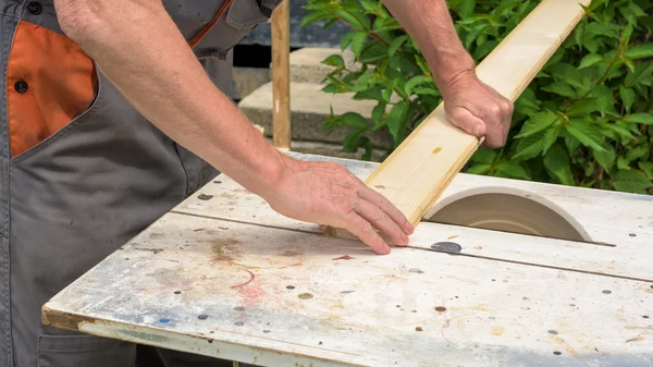 Carpenter working with electric buzz saw cutting wooden boards — Stock Photo, Image