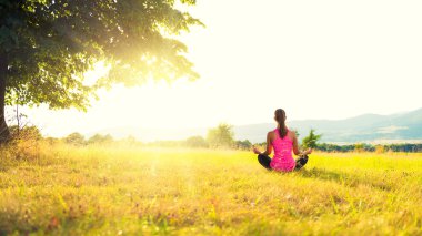 Pratik Yoga bir çayır mercek parlaması ile günbatımı, görüntü üzerinde genç atletik kadın